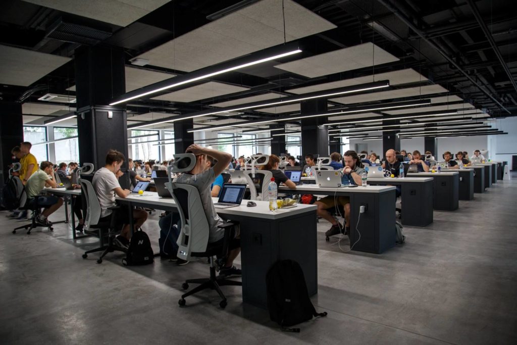 Minimalist open plan office with men and women working attentively on their Macbooks while seated at desks (Photo by Alex Kotliarskyi on Unsplash)