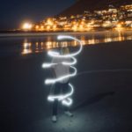 Man on beach at night surrounded by swirling light