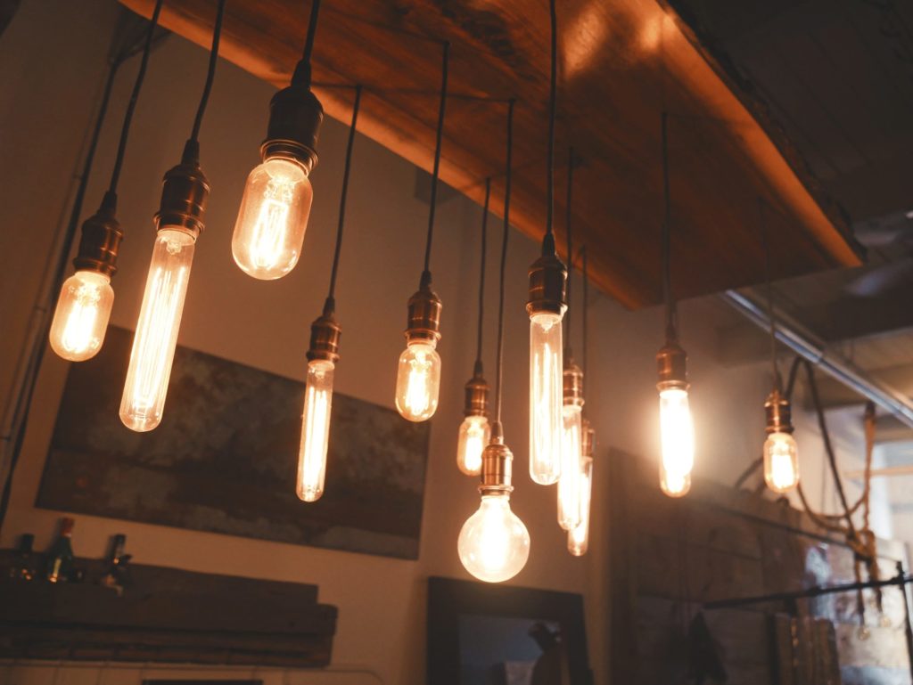A variety of glowing Edison-style lightbulbs hang from the ceiling (Photo by Patrick Tomasso on Unsplash)