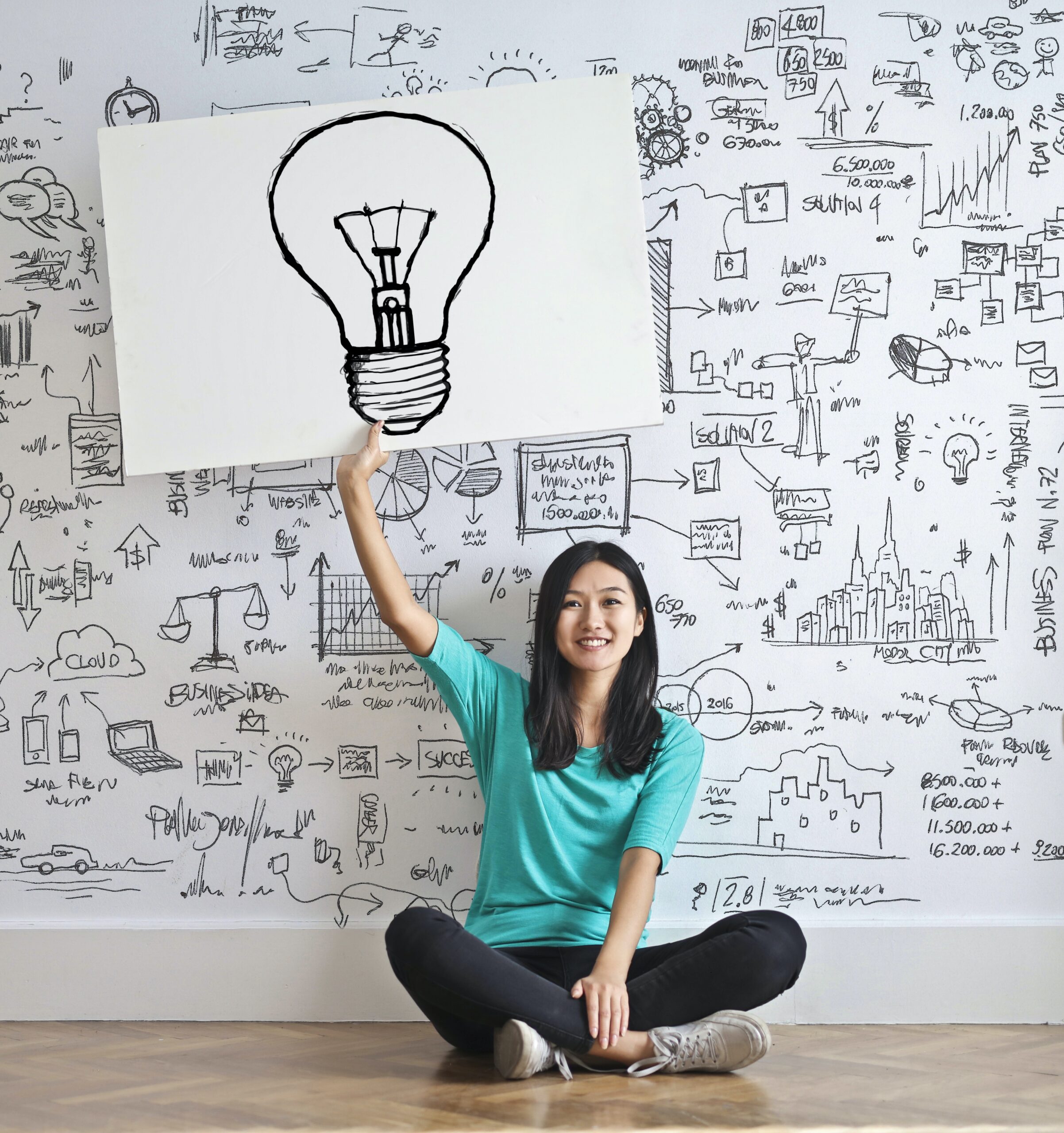 Person sitting on floor holding up a picture of a lightbulb