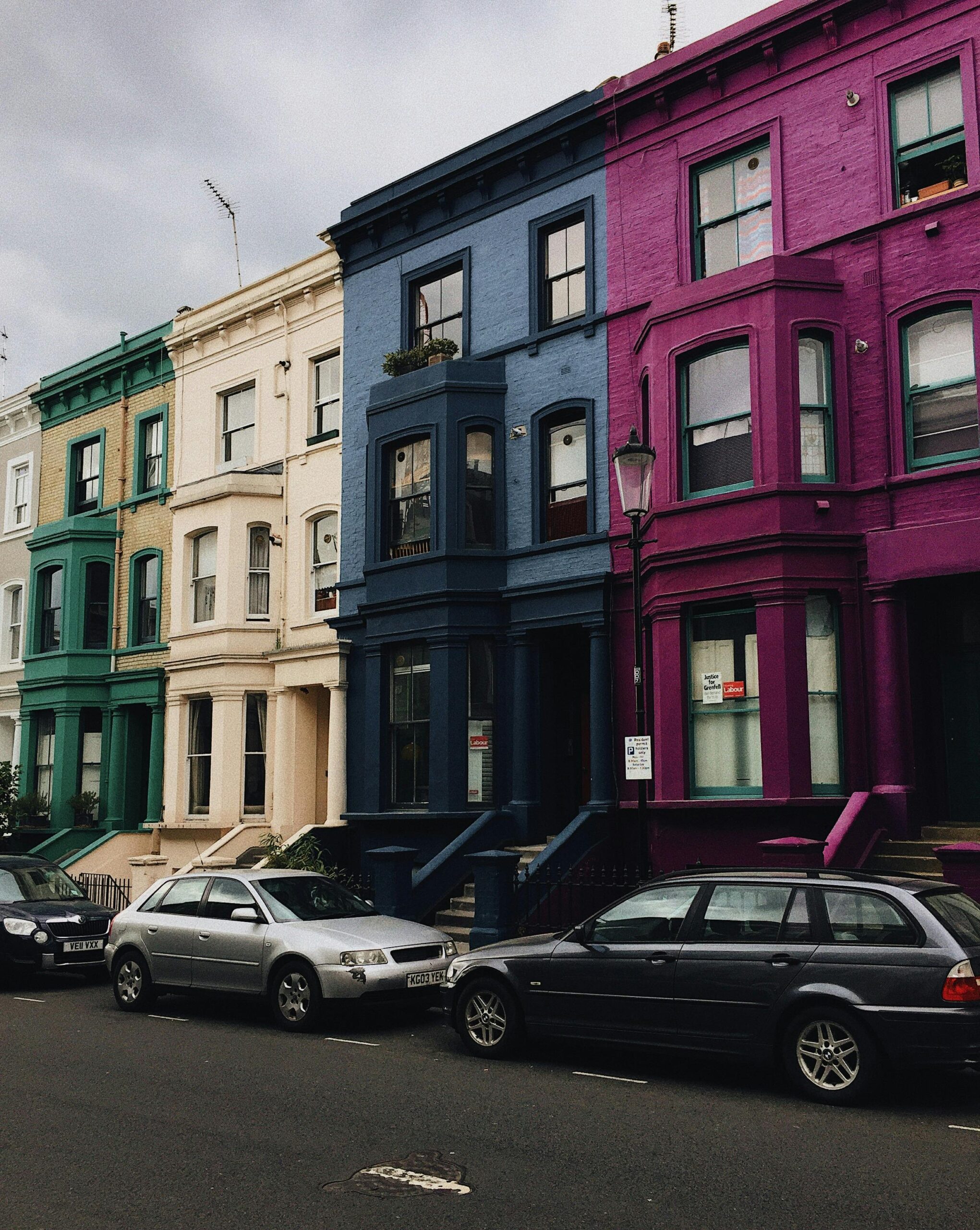 Cars parked in front of colourful houses. Photo by Lina Kivaka from Pexels.